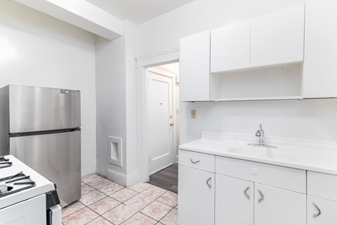 A kitchen with white cabinets and a stainless steel refrigerator.