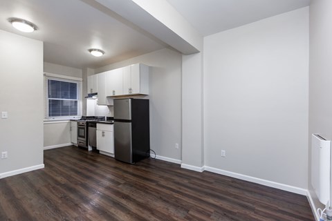 A kitchen with white cabinets and a black refrigerator.