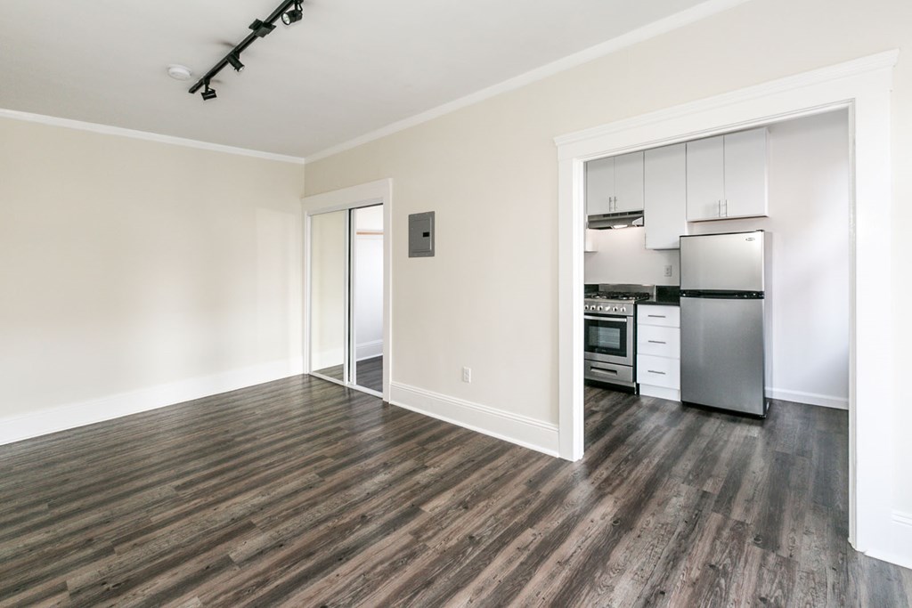 a living room with wood floors and a kitchen with stainless steel appliances