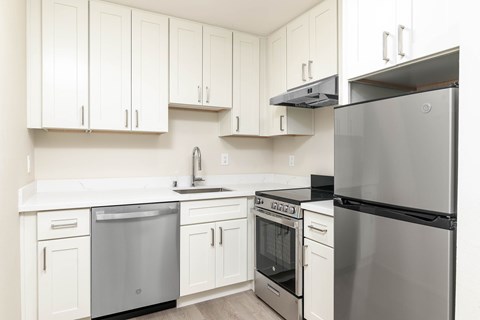 A modern kitchen with white cabinets and stainless steel appliances.