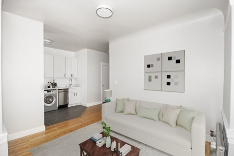 A white couch with green pillows sits in a living room with a coffee table in front of it.