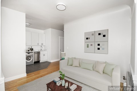 A white couch with green pillows sits in a living room with a wooden coffee table in front of it.