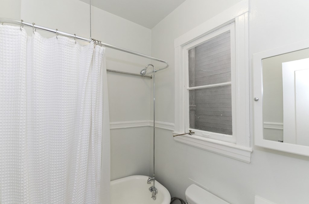 a white bathroom with a shower curtain and a window