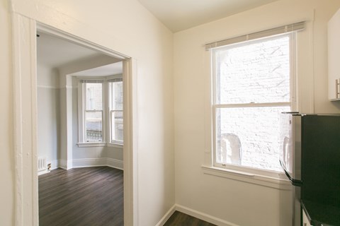 A room with a window and a doorway leading to another room.