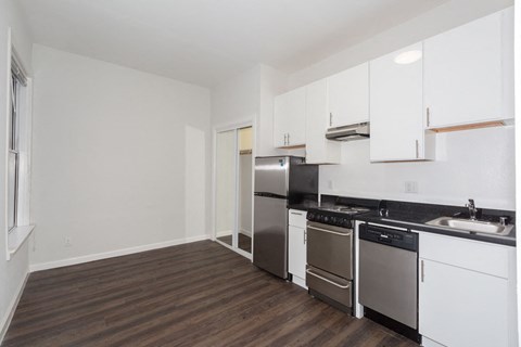 A kitchen with white cabinets and a black countertop.
