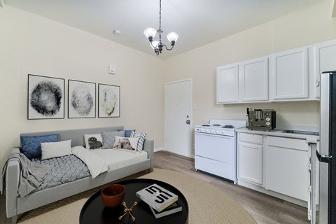A white bedroom with a bed, a table, and a fridge.