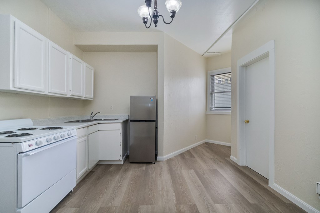 A kitchen with white appliances and wooden floors.