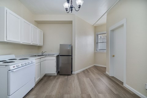 A kitchen with white appliances and wooden floors.