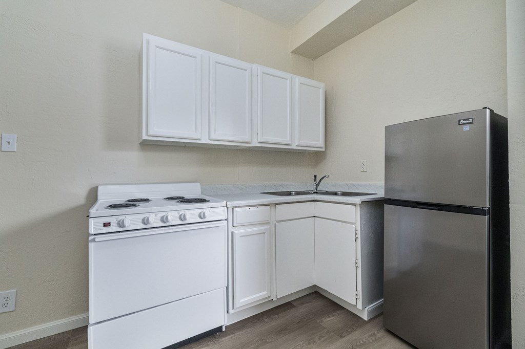A kitchen with a white stove and white cabinets.