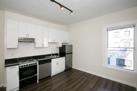 A kitchen with white cabinets and black countertops.