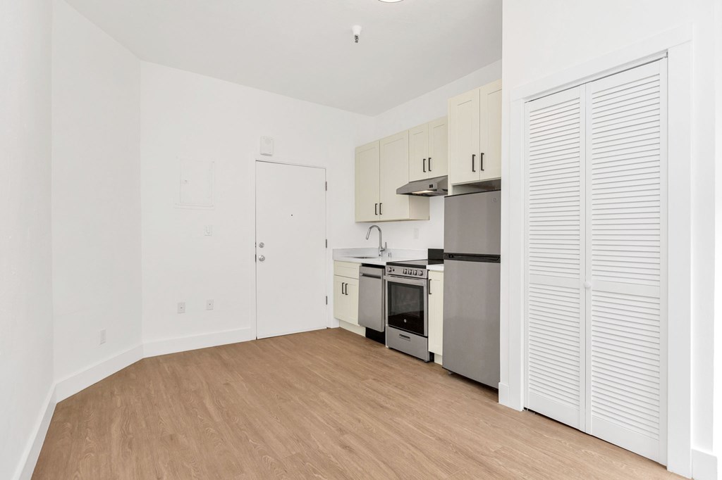 A kitchen with white cabinets and a wooden floor.