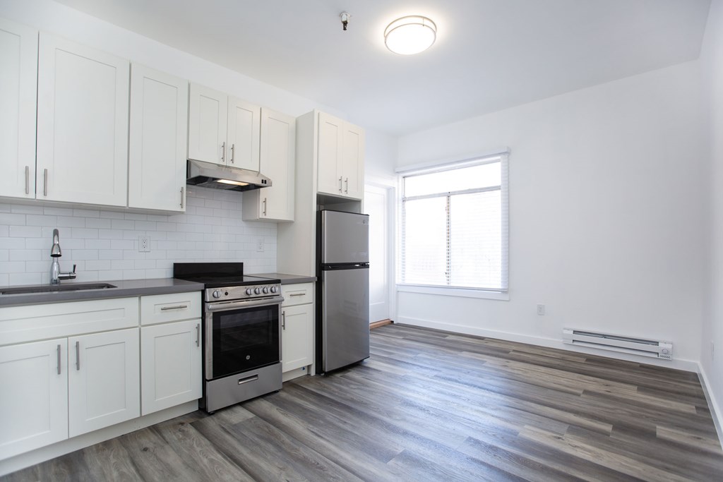 A kitchen with white cabinets and a stainless steel refrigerator.