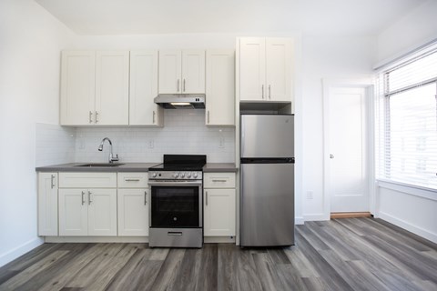 A kitchen with white cabinets and a stainless steel refrigerator.