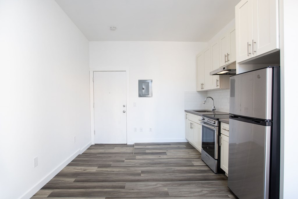 A kitchen with a stainless steel refrigerator and wooden flooring.