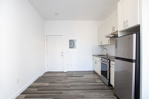 A kitchen with a stainless steel refrigerator and wooden flooring.