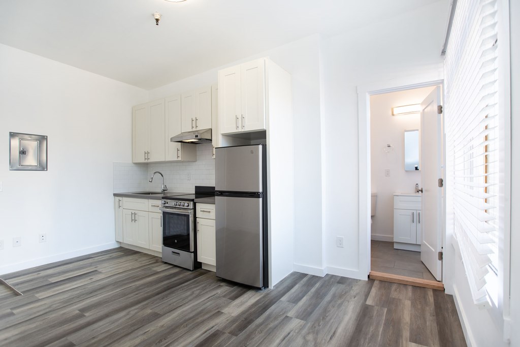A kitchen with white cabinets and a stainless steel refrigerator.