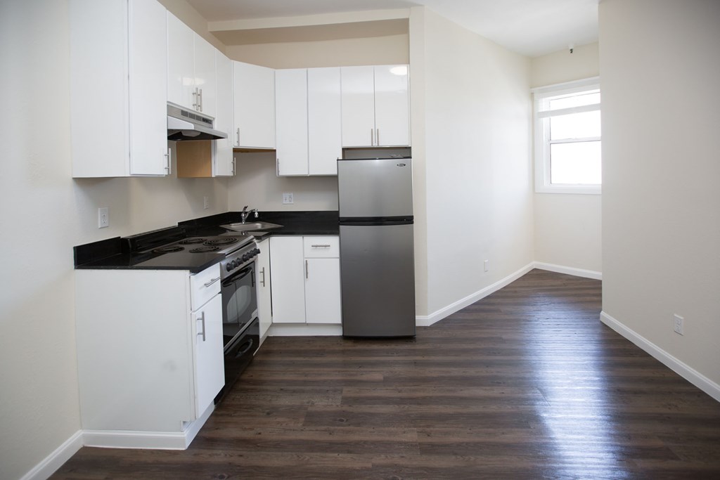 A kitchen with white cabinets and black countertops.