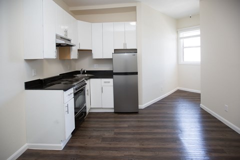 A kitchen with white cabinets and black countertops.