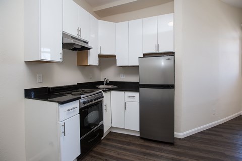A kitchen with white cabinets and black countertops.