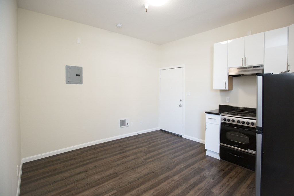 A kitchen with a black fridge and white cabinets.