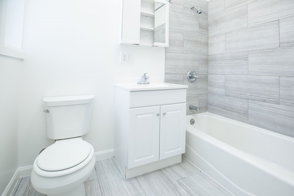 A white toilet sits next to a white cabinet in a bathroom.
