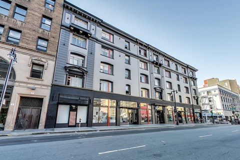 A street view of a row of buildings with shops on the ground floor.