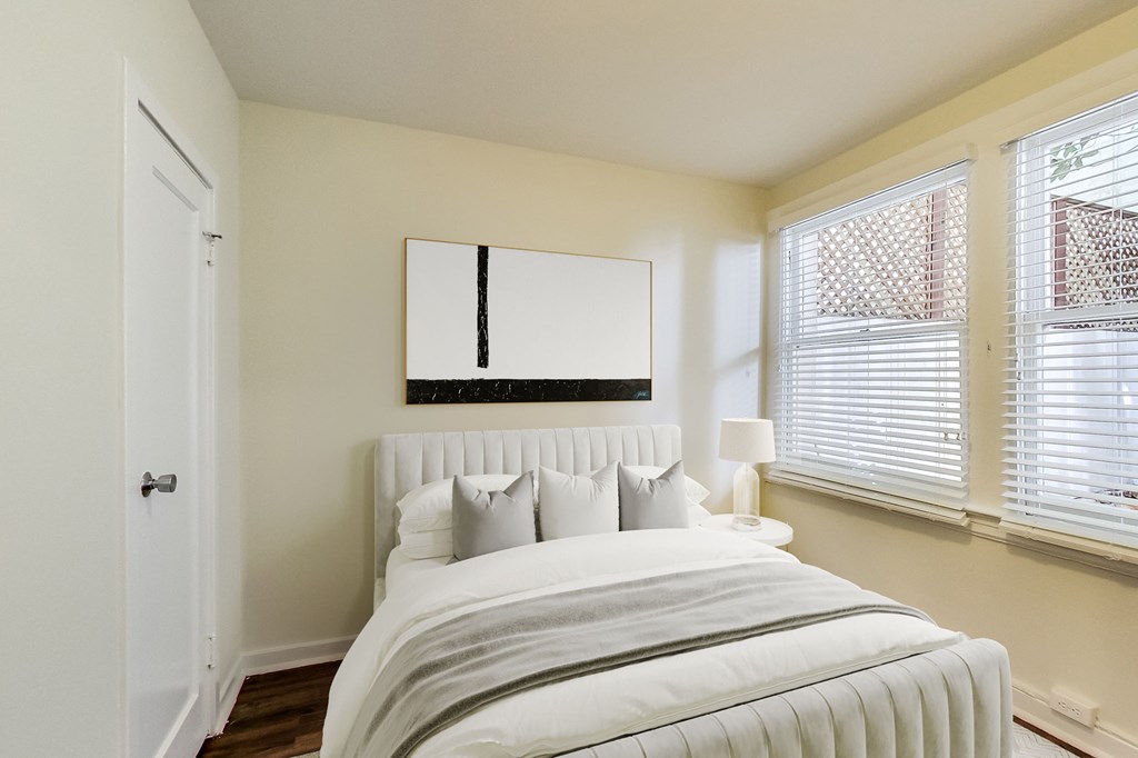 a bedroom with a large bed and two windows