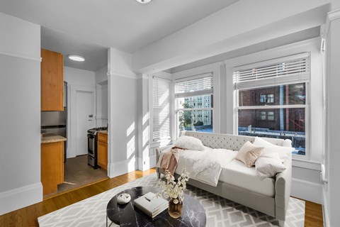 A living room with a white couch and a coffee table with a vase of flowers on it.