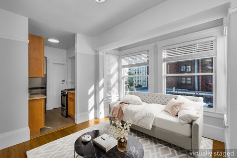 A living room with a white couch and a coffee table with a vase of flowers on it.