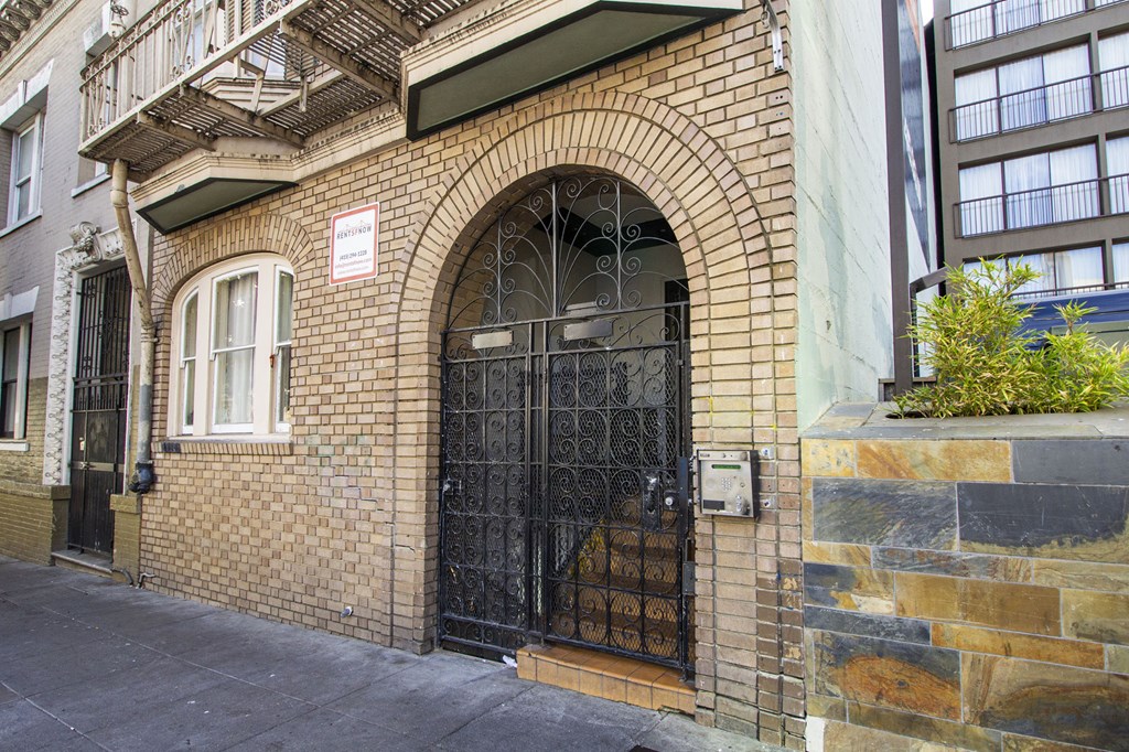 a brick building with a black door and a wrought iron gate