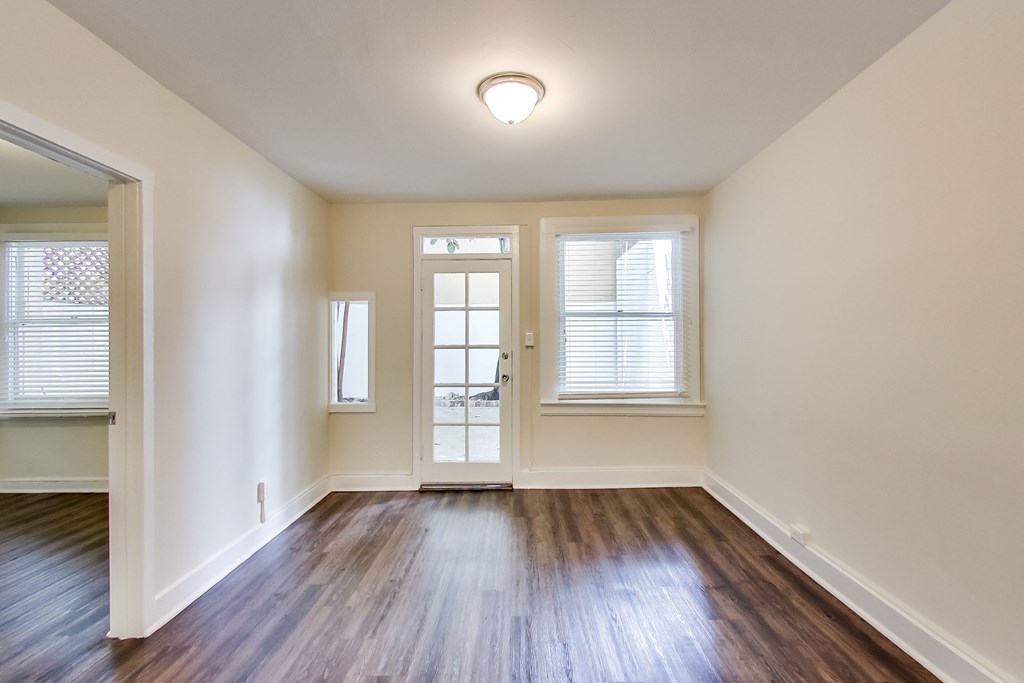 an empty living room with hardwood flooring and a door to a balcony