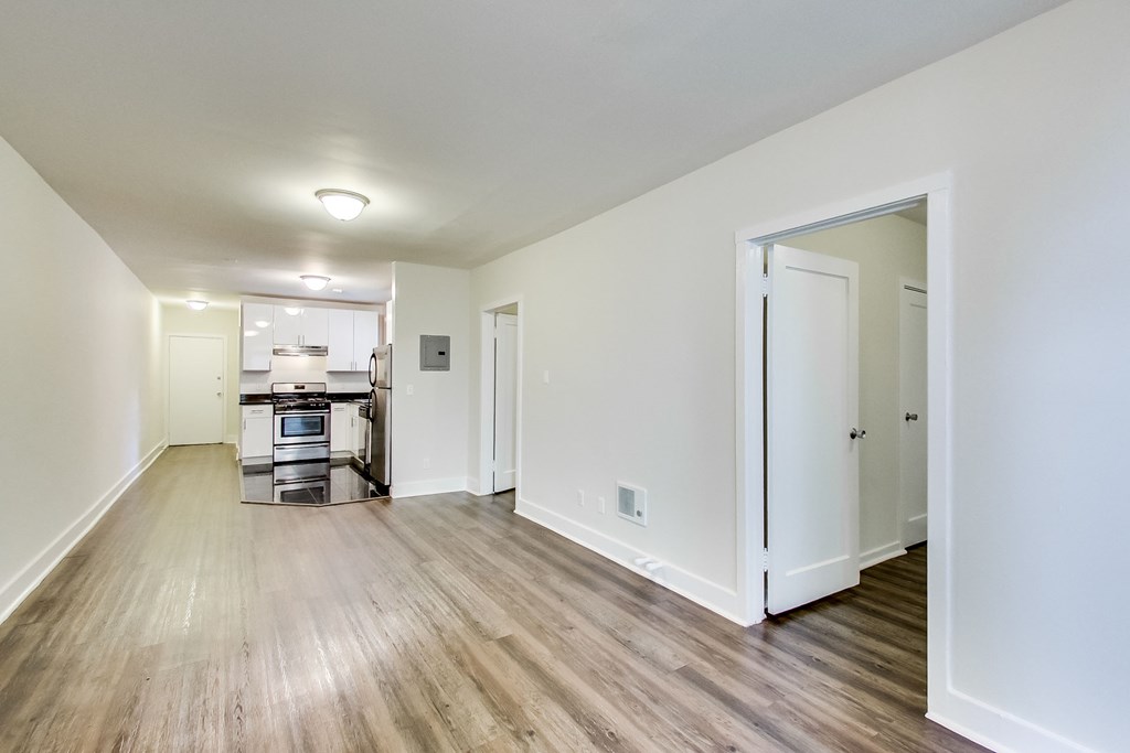 a renovated living room and kitchen with wood floors and white walls