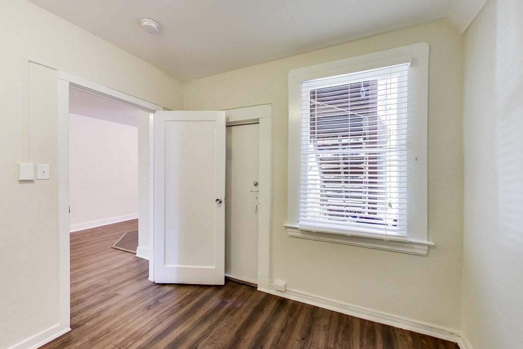 a bedroom with a large window and wood flooring and a closet