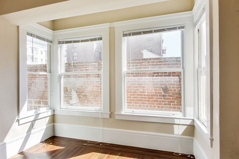 A room with a window overlooking a brick wall.