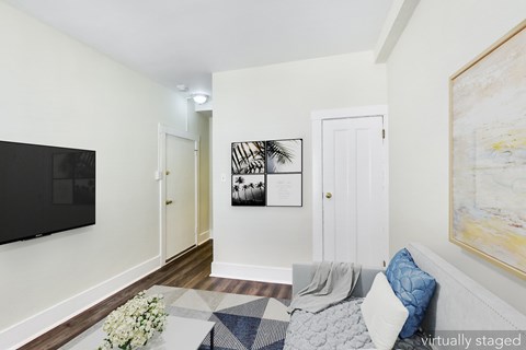 A living room with a grey sofa and a painting on the wall.