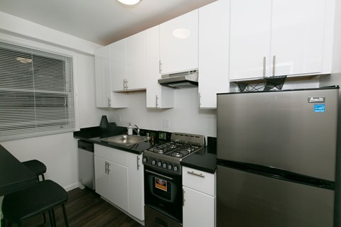 A kitchen with white cabinets and a black counter.