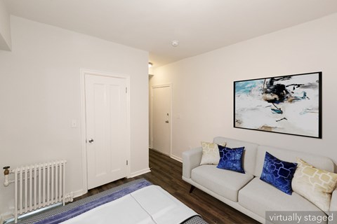 A living room with a white couch and a painting on the wall.