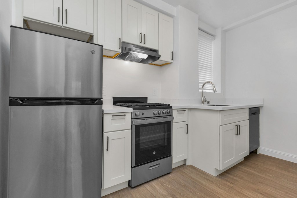a kitchen with white cabinets and stainless steel appliances and a refrigerator
