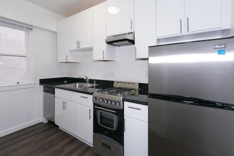 A kitchen with white cabinets and a stainless steel refrigerator.