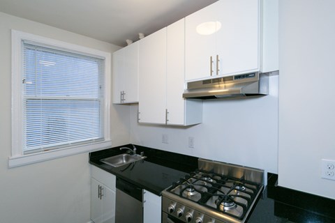 A kitchen with white cabinets and a black countertop.