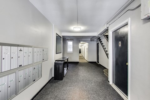 A long hallway with a black door on the right and a staircase on the left.