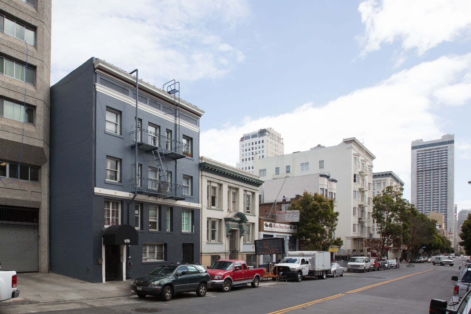A street view of a city with cars parked on the side of the road.