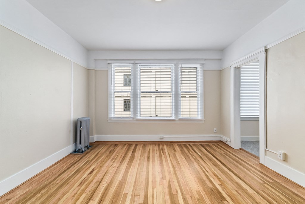 A room with wooden flooring and a window with blinds.