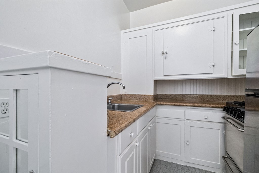 A kitchen with white cabinets and a granite countertop.