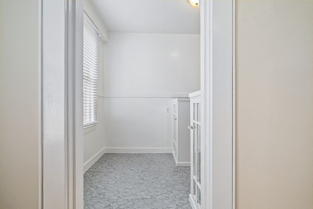 A white door is open to a room with a tiled floor.
