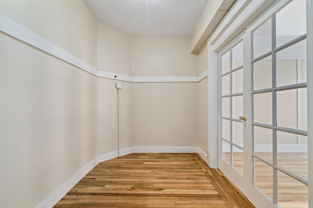 A room with a white door and wooden floor.