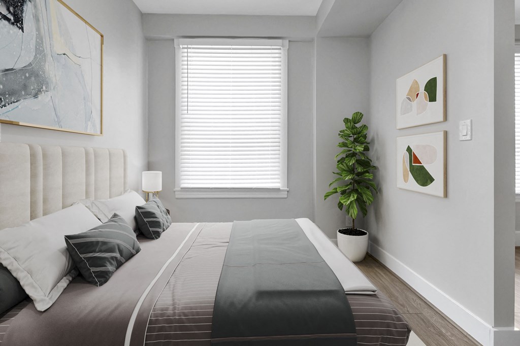 A bedroom with a large bed and a potted plant.