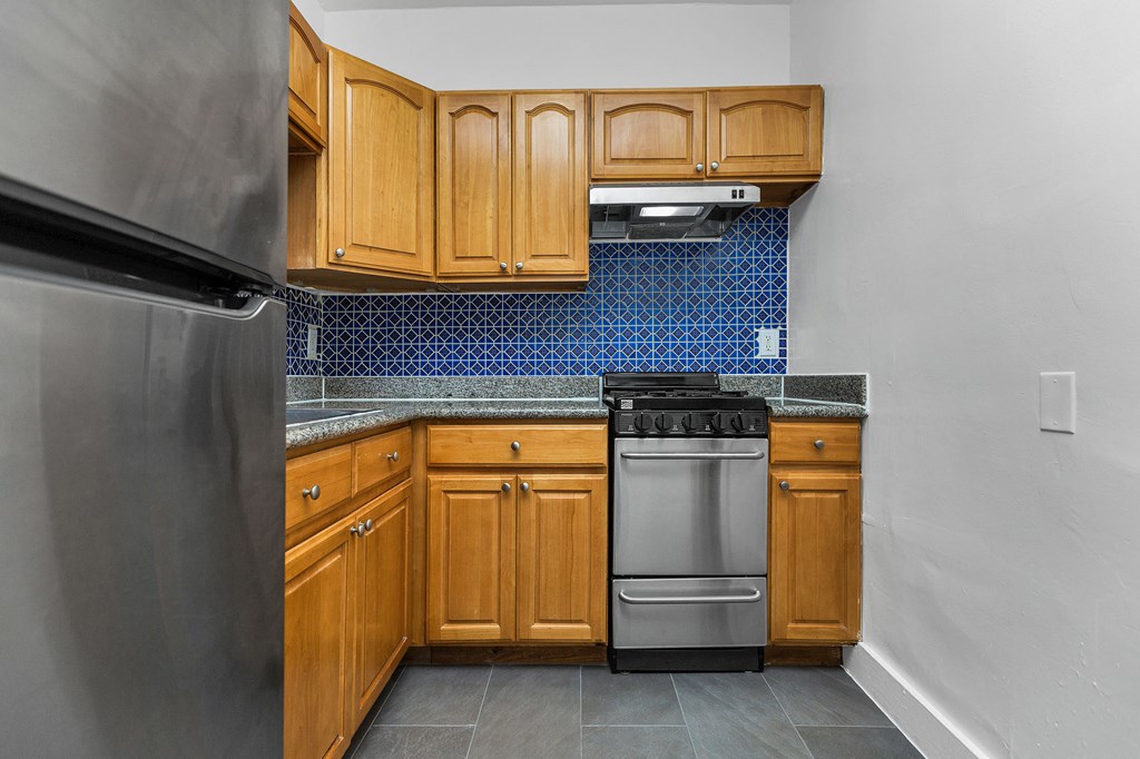 A kitchen with wooden cabinets and a stainless steel refrigerator.