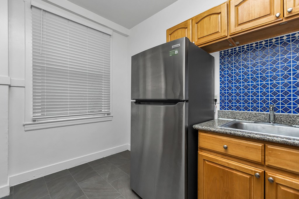A kitchen with a black fridge and wooden cabinets.