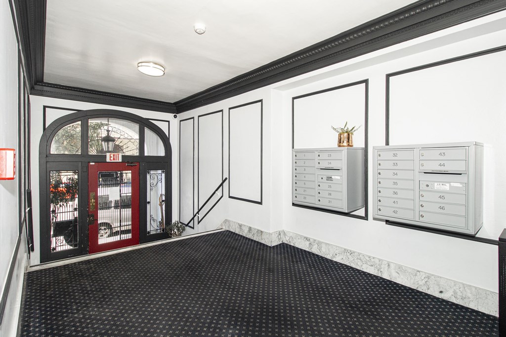 A hallway with a red door and a white wall with a calendar on it.